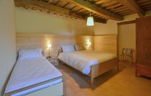 Ein Schlafzimmer mit zwei Betten, hölzernen Kopfteilen, einer Pendelleuchte und einem Holzschrank.