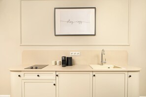 A kitchenette with a framed sign, a coffee maker, and a sink. - Vucino Suites (Istanbul)
