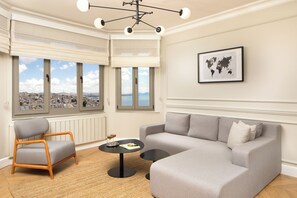 A modern living room with a grey sofa, a wooden chair, a round black table, and a world map on the wall. - Vucino Suites (Istanbul)