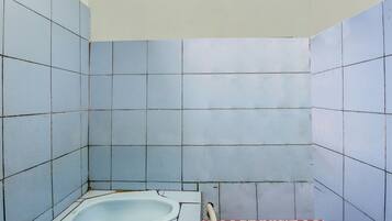 A small, tiled bathroom with a single bathtub and a shower area.