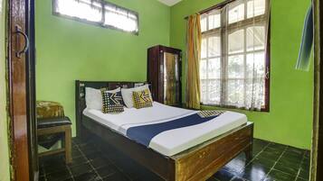 A room with a bed, a wooden cabinet, a window with curtains, and a small stool.