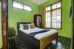 A room with a bed, a wooden cabinet, a window with curtains, and a small stool. - OYO Homes 91155 Desa Wisata Selamanik Ciamis (Kawali)