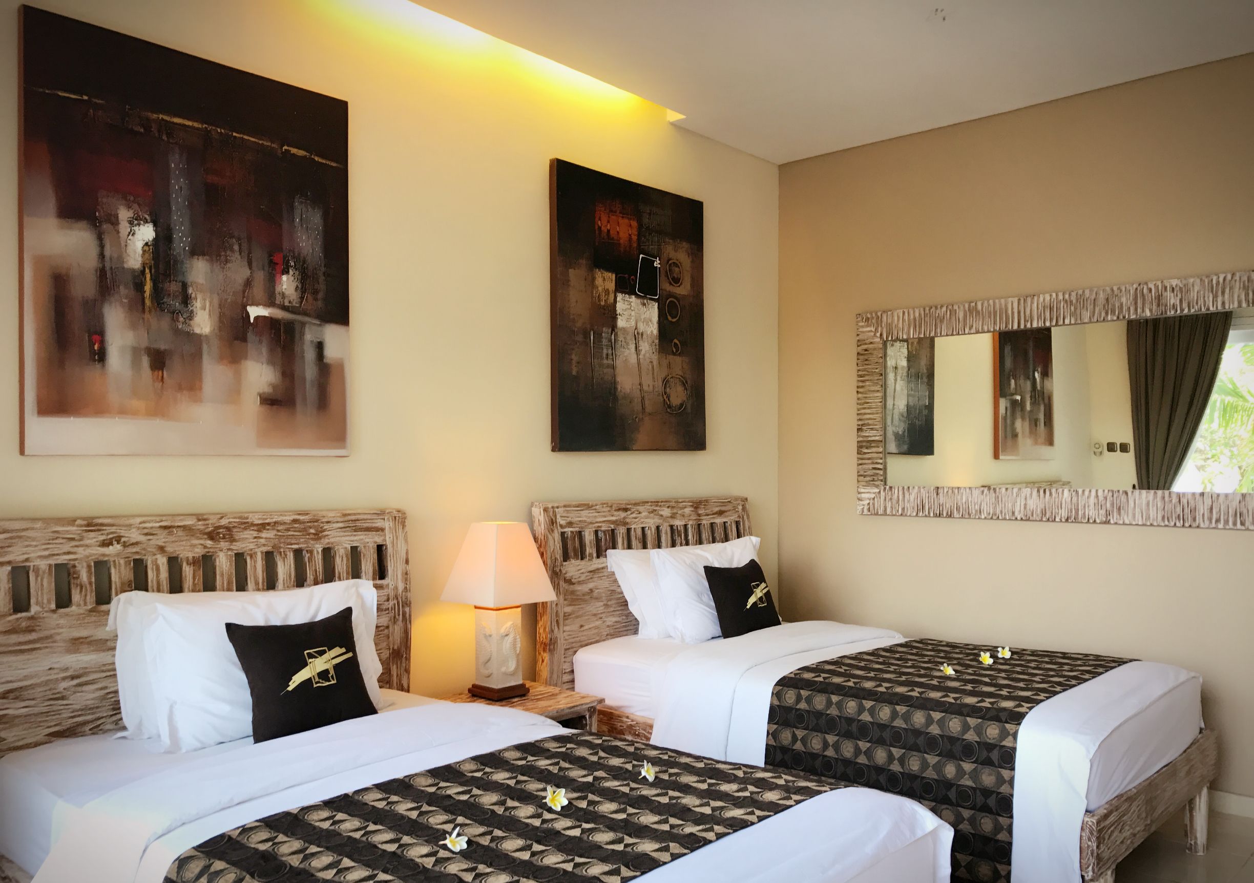 A hotel room with two beds, a large abstract painting, a mirror, and a lamp.