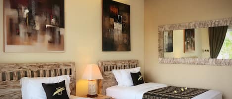 A hotel room with two beds, a large abstract painting, a mirror, and a lamp.