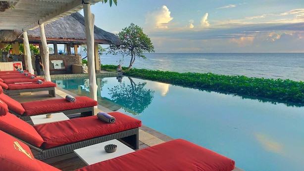 A poolside area with lounge chairs and a view of the sea.