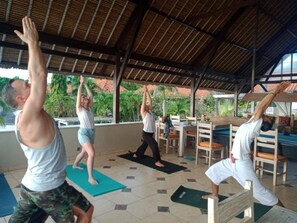 A covered outdoor area with people performing yoga. - Tauch Terminal Resort Tulamben & Spa (Rendang)