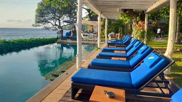 Un área junto a la piscina con sillones de descanso y una pérgola.