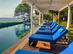 A poolside area with lounge chairs and a pergola. - Tauch Terminal Resort Tulamben & Spa (Rendang)