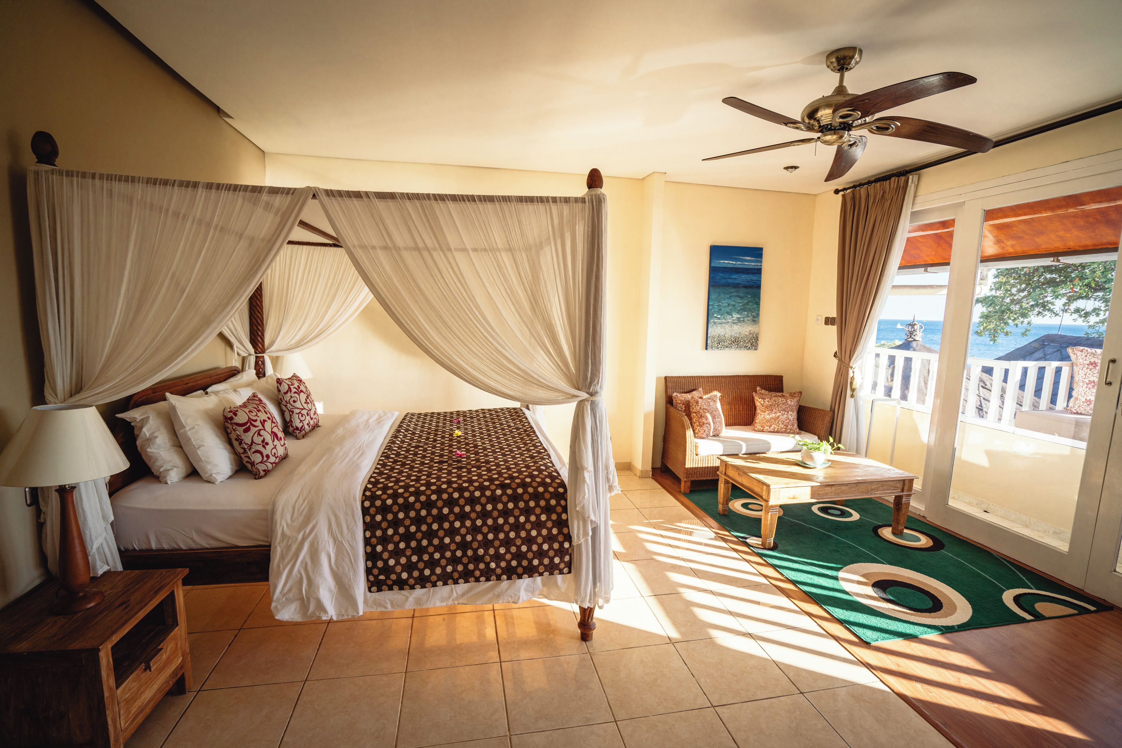 Un dormitorio con cama con dosel, ventilador de techo, vista al exterior y balcón.