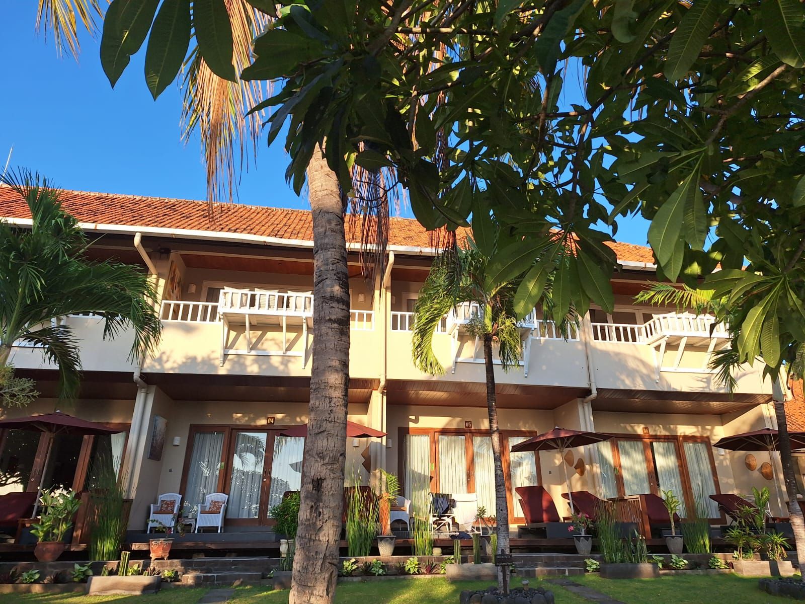 A two-story building with a balcony, outdoor seating, and a well-maintained garden.