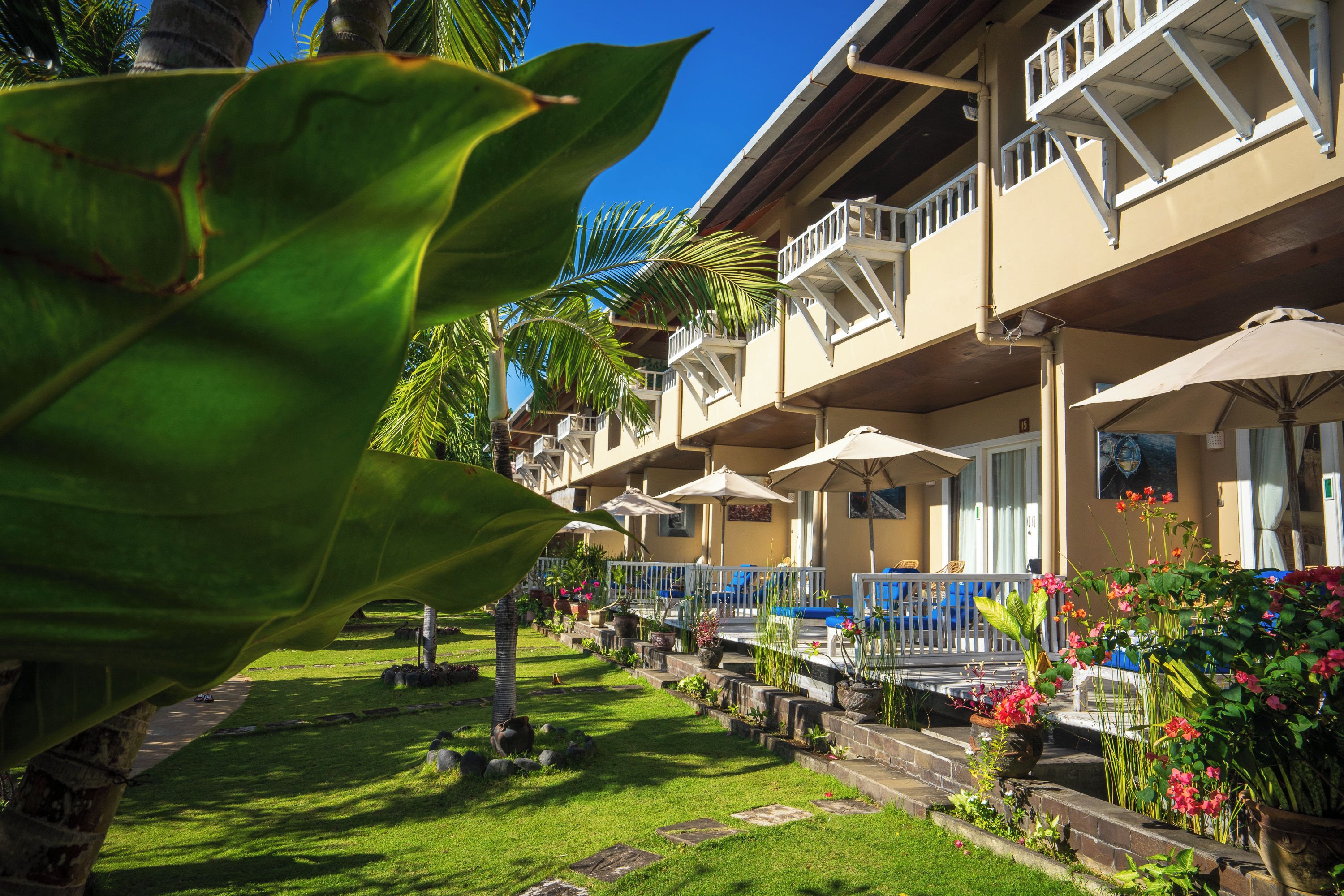 A hotel with multiple balconies, outdoor seating, and a well-maintained garden.