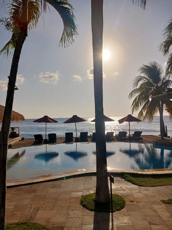A poolside view with lounge chairs and umbrellas, overlooking the sea.