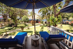 A patio with blue lounge chairs, a wooden table, and a large umbrella.