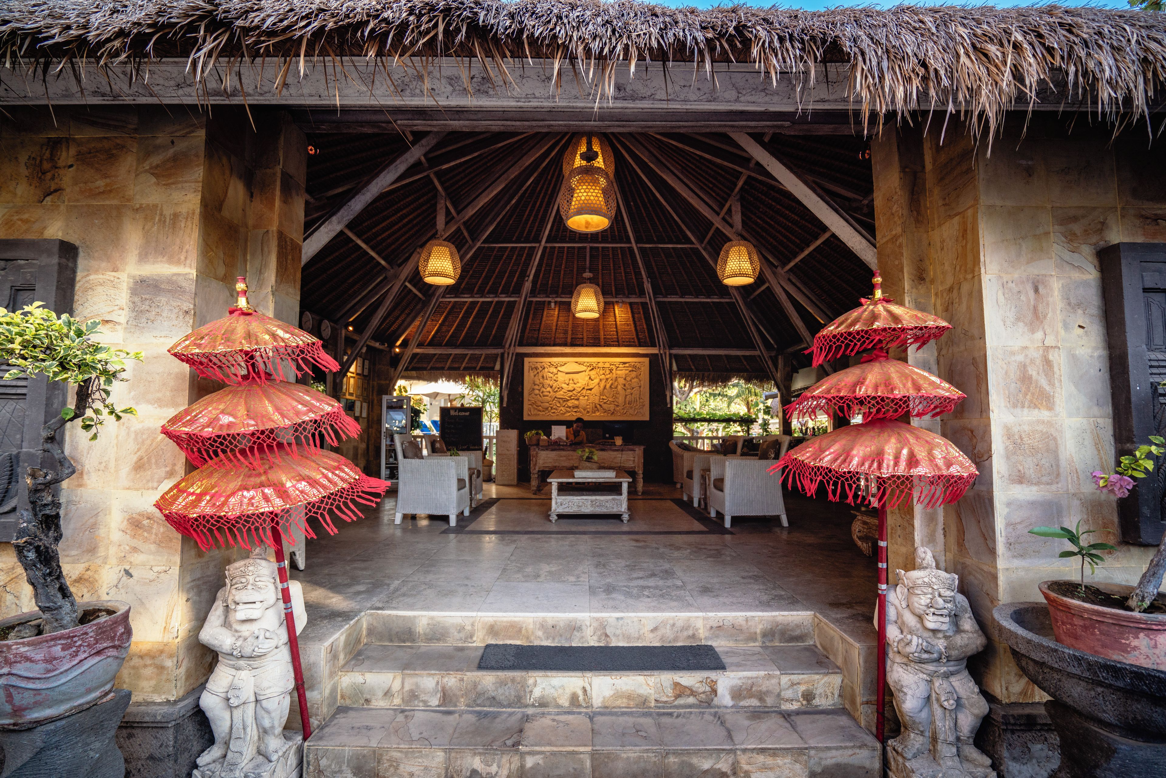 A traditional building with a thatched roof, stone walls, and a central seating area with a low table and chairs.