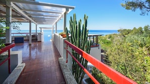 A covered outdoor area with a view of the sea, a cactus, and a red railing. - Beautiful home in Sperlonga (Sperlonga)