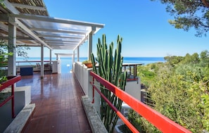 A covered outdoor area with a view of the sea, a cactus, and a red railing. - Beautiful home in Sperlonga (Sperlonga)