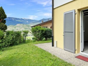 Ein Gebäude mit offener Tür, einem Kiesweg und Blick auf Berge.