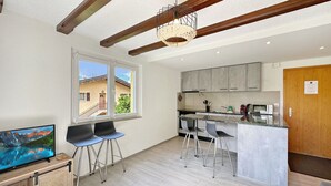 Una cocina moderna con taburetes de bar, techo de madera y un ventanal grande.