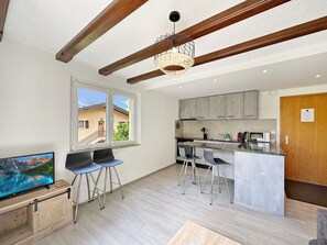 Una cocina moderna con taburetes de bar, techo de madera y un ventanal grande.