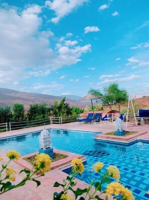 A swimming pool with a view of mountains, lounge chairs, and decorative urns. - Les Jardins Yasmina (Sidi Dahmane)