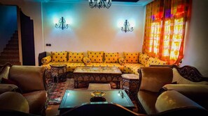 A living room with a sofa set, two armchairs, a coffee table, and a chandelier. - Les Jardins Yasmina (Sidi Dahmane)