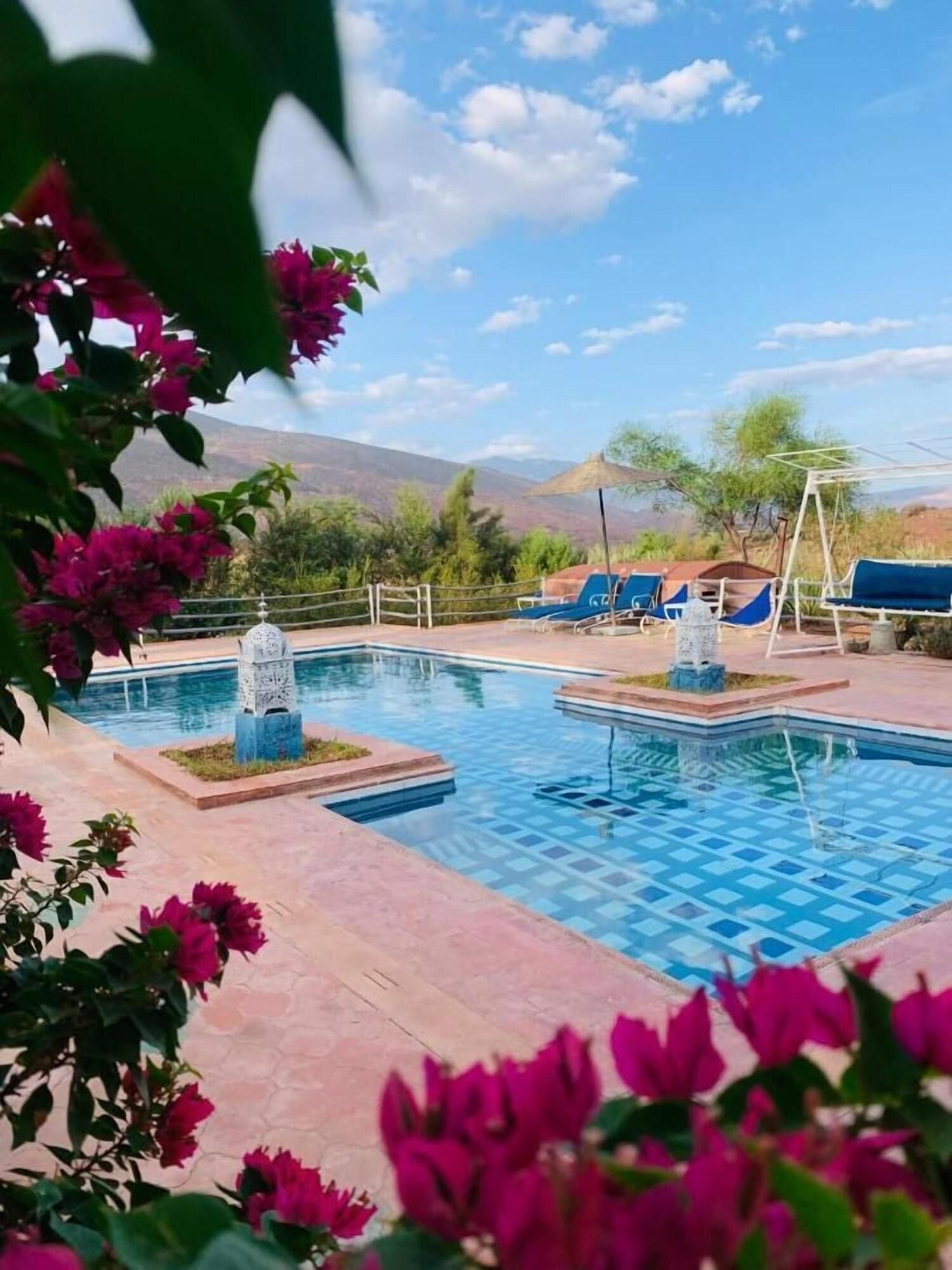 A pool area with lounge chairs and a view of mountains.