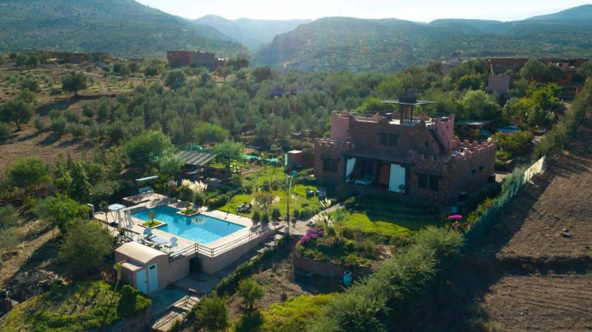Une villa avec piscine, entourée d’une végétation luxuriante et de montagnes.