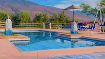 A poolside view with a fruit plate, a glass of juice, and a table.