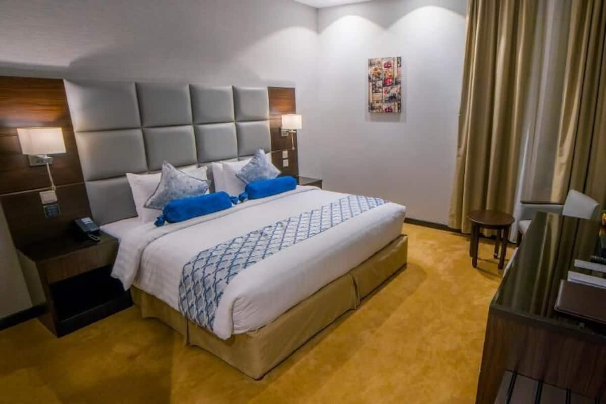 Une chambre d’hôtel avec un grand lit, des tables de chevet avec des lampes, une télévision et un bureau avec un ordinateur.