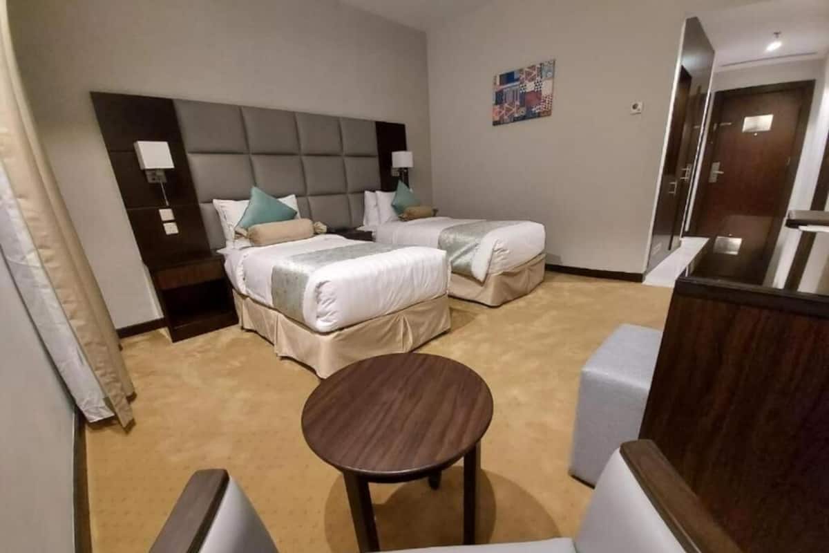 Une chambre d’hôtel avec deux lits, une petite table ronde et un coin salon.