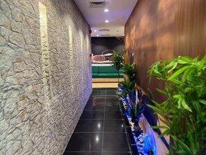 A corridor with stone walls, a green sofa, and a reception desk. - Holiday Villahail (Ha'il)