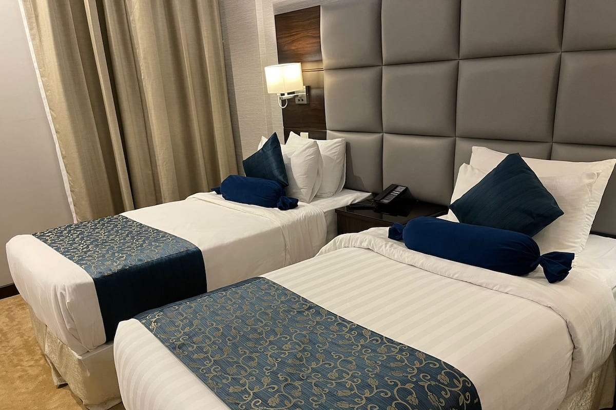 Une chambre d’hôtel avec deux lits, une table de chevet avec un téléphone et une lampe.