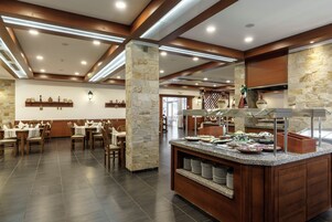 Un restaurante con bufé, sillas de madera, pilares de piedra y una pared de piedra.