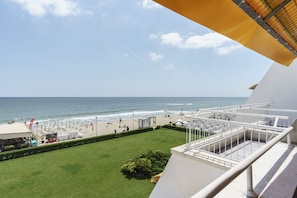 A balcony with a view of the beach and ocean.