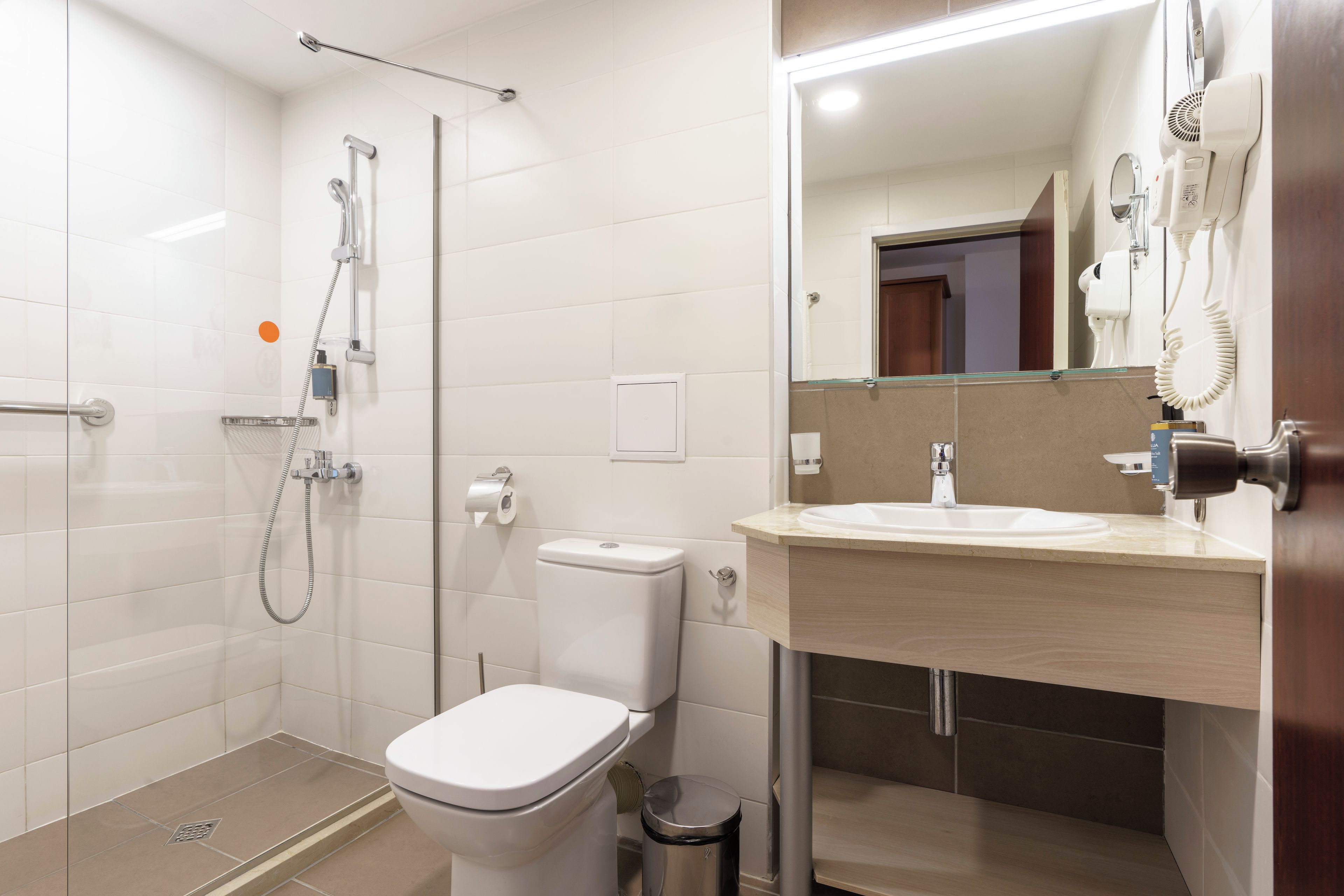 Une salle de bain moderne équipée d’une douche, de toilettes, d’un lavabo et d’un miroir.