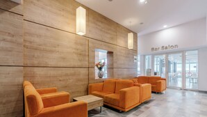 A modern bar salon with wooden walls, orange seating, and a view through the glass doors. - Aluasun Helios Beach (Nessebar)