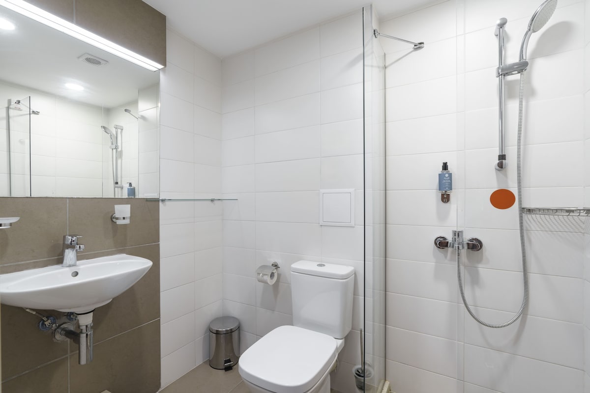 Et moderne badeværelse med vask, toilet og bruser.