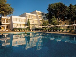 Un hotel con piscina, tumbonas y sombrillas.