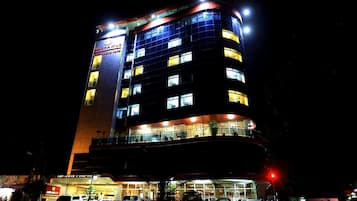 A multi-story hotel with illuminated windows and a sign indicating it is a hotel.