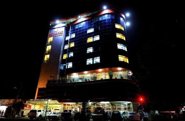 A multi-story hotel with illuminated windows and a sign indicating it is a hotel.