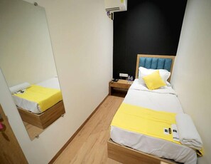 A small hotel room with two beds, a mirror, a nightstand, and a wall-mounted air conditioner. - Cabinstay Airport (Mumbai)