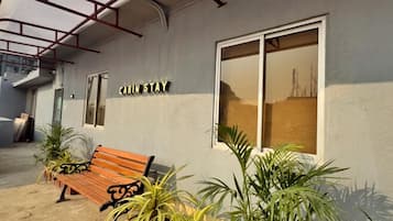 A building with a sign reading 'CABIN STAY' and a wooden bench with potted plants in front.
