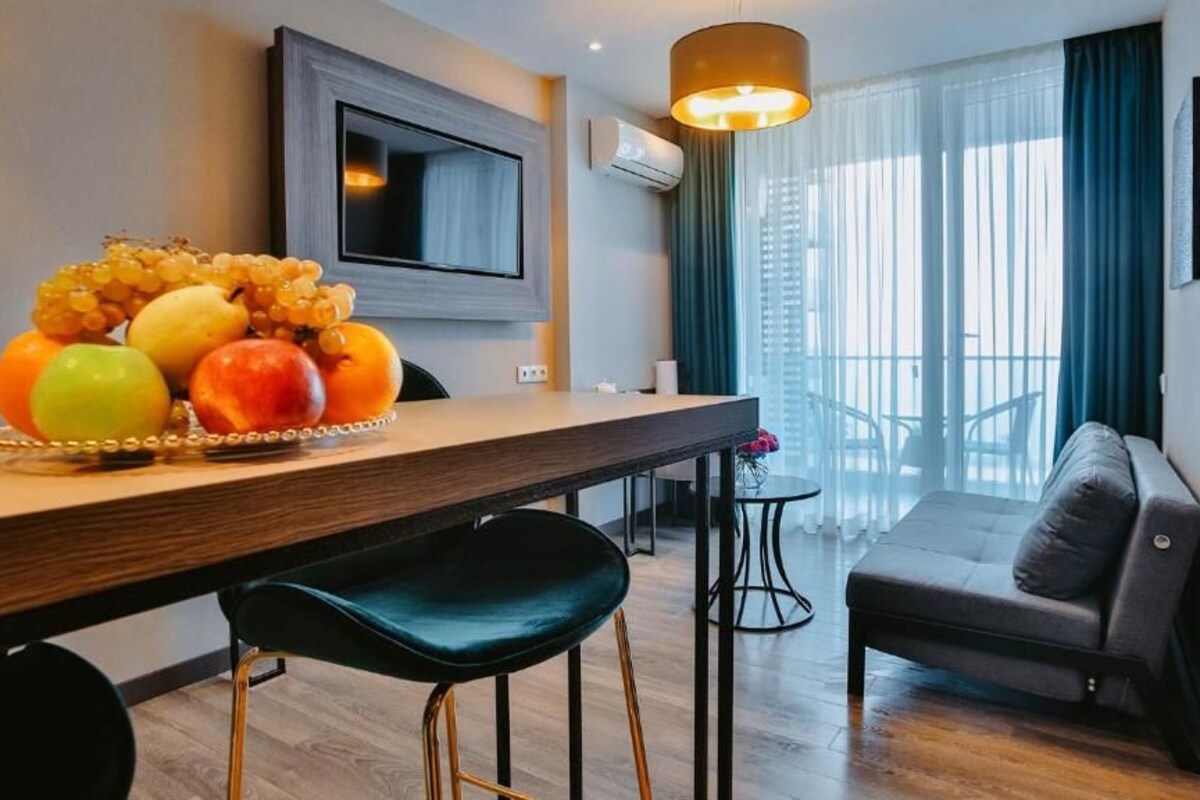 Ein modernes Hotelzimmer mit einem Holztisch, einer Couch und einem an der Wand befestigten Fernseher.