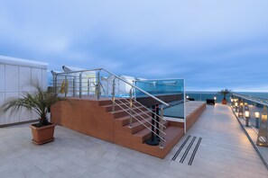 Eine Dachterrasse mit Glasgeländer, einer Treppe und einem Blumentopf.