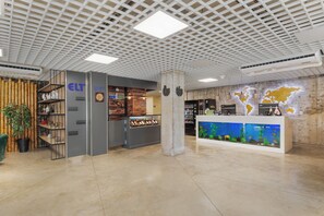 Eine moderne Lobby mit einer Weltkarte, einem Empfangstresen und einer Bambuspflanze.