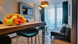 Ein modernes Hotelzimmer mit Essbereich, einer Couch und einem Fernseher.