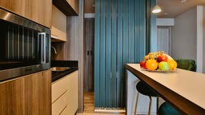 Une cuisine moderne dotée d’une hotte en acier inoxydable, de meubles en bois et d’un panier à fruits posé sur le plan de travail.