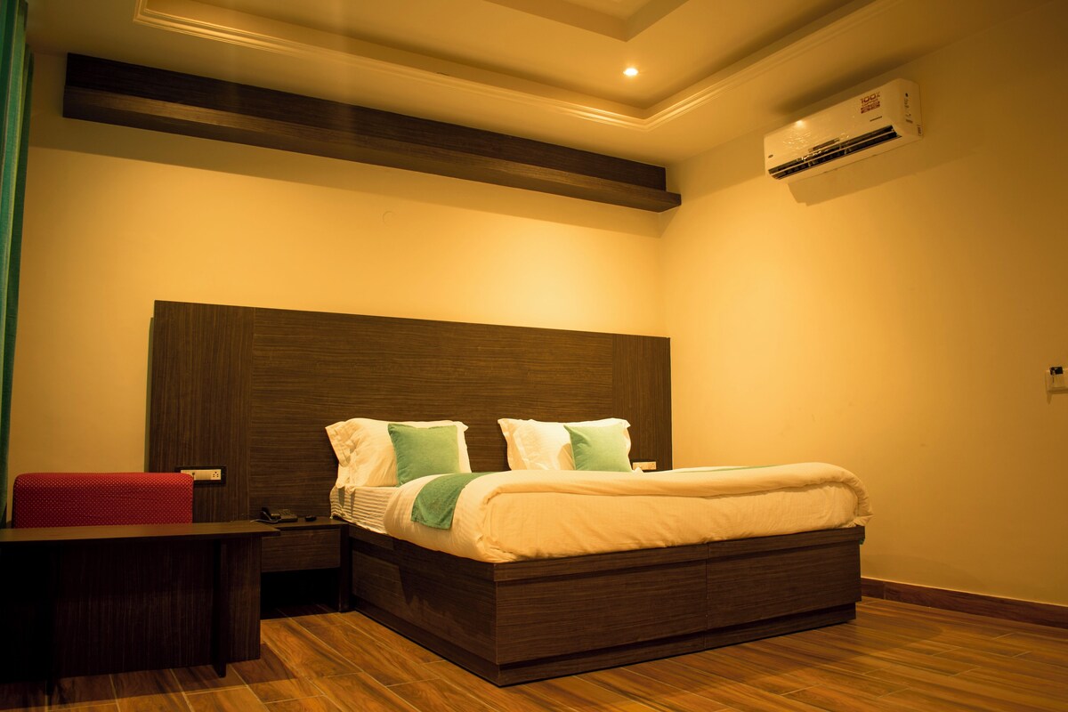A bedroom with a bed, bedside table, and an air conditioning unit.