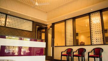 A reception area with a reception desk, three chairs, a ceiling fan, and decorative wall panels.