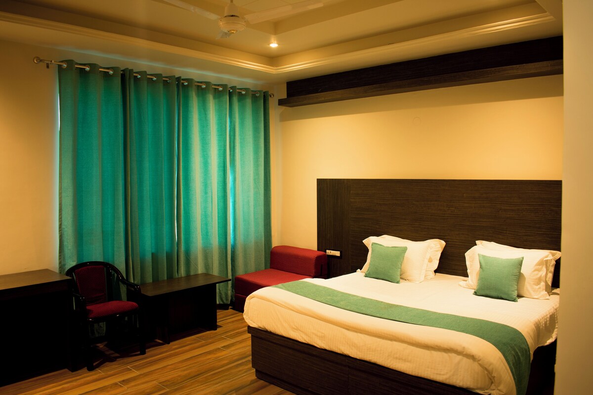 A hotel room with a bed, a desk, a chair, and a red sofa.